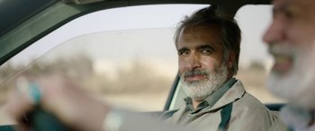 Movie still from “Holy Spider” (2022), directed by Ali Abbasi – A man sitting in the driver's seat of a car; Close Up shot, Over the shoulder angle