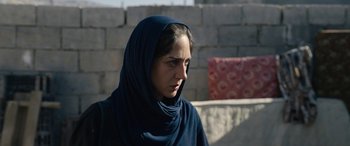 Movie still from “Holy Spider” (2022), directed by Ali Abbasi – A woman with a blue head scarf is standing in front of a brick wall; Close Up shot, Over the shoulder angle