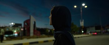 Movie still from “Holy Spider” (2022), directed by Ali Abbasi – A person wearing a headscarf is standing on the side of the road; Close Up shot, Low angle