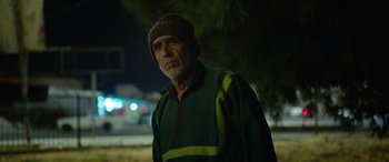 Movie still from “Holy Spider” (2022), directed by Ali Abbasi – An older man wearing a green jacket and a brown hat; Close Up shot, Over the shoulder angle