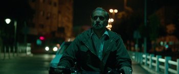 Movie still from “Holy Spider” (2022), directed by Ali Abbasi – A man riding a bike down a street at night; Medium shot, Low angle