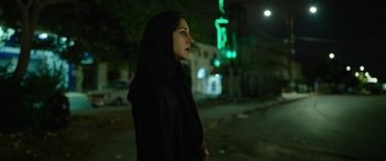 Movie still from “Holy Spider” (2022), directed by Ali Abbasi – A woman wearing a black veil standing on the side of the road; Close Up shot, Low angle