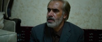 Movie still from “Holy Spider” (2022), directed by Ali Abbasi – A man in a suit and tie looking to his left; Close Up shot, Over the shoulder angle