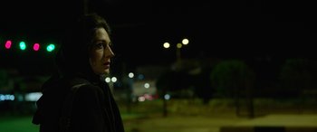 Movie still from “Holy Spider” (2022), directed by Ali Abbasi – A woman standing in the dark with lights in the background; Close Up shot, Low angle