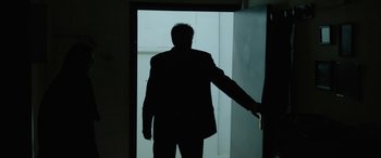 Movie still from “Holy Spider” (2022), directed by Ali Abbasi – A man standing in front of an open door; Medium shot, Low angle