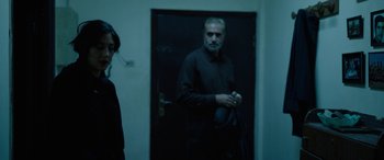 Movie still from “Holy Spider” (2022), directed by Ali Abbasi – A man standing in front of an open door; Medium shot, Over the shoulder angle