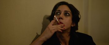 Movie still from “Holy Spider” (2022), directed by Ali Abbasi – A woman is holding a lit cigarette in her mouth; Close Up shot, High angle