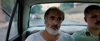 Movie still from “Holy Spider” (2022), directed by Ali Abbasi – A man sitting in the back seat of a car; Close Up shot, High angle