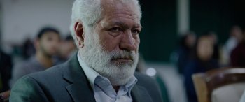 Movie still from “Holy Spider” (2022), directed by Ali Abbasi – An older man with a beard and a white beard; Close Up shot, Over the shoulder angle