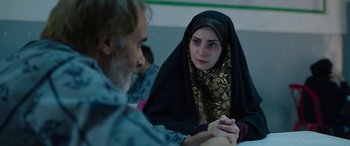 Movie still from “Holy Spider” (2022), directed by Ali Abbasi – A woman wearing a headscarf is sitting next to an older man; Close Up shot, Over the shoulder angle