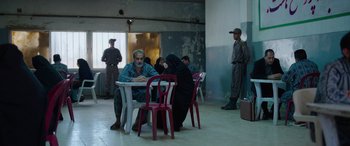 Movie still from “Holy Spider” (2022), directed by Ali Abbasi – A group of people sitting at a table in a room; Wide shot, Over the shoulder angle