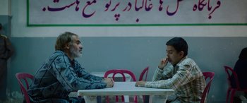 Movie still from “Holy Spider” (2022), directed by Ali Abbasi – Two people sitting at a table in a restaurant; Medium shot, Over the shoulder angle