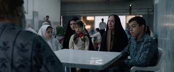 Movie still from “Holy Spider” (2022), directed by Ali Abbasi – A group of women standing around a table; Medium shot, Over the shoulder angle