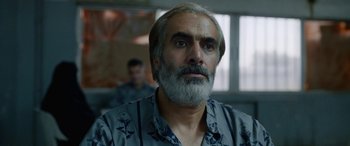 Movie still from “Holy Spider” (2022), directed by Ali Abbasi – A person with a gray beard; Close Up shot, Over the shoulder angle