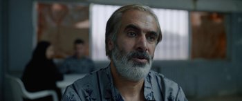 Movie still from “Holy Spider” (2022), directed by Ali Abbasi – A person with a gray beard; Close Up shot, Over the shoulder angle