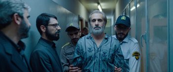 Movie still from “Holy Spider” (2022), directed by Ali Abbasi – A group of men standing next to each other in a hallway; Medium shot, Over the shoulder angle