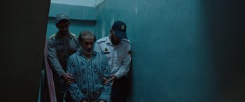 Movie still from “Holy Spider” (2022), directed by Ali Abbasi – A police officer is standing next to an older man; Medium shot, Over the shoulder angle