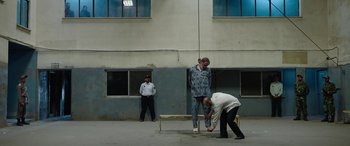 Movie still from “Holy Spider” (2022), directed by Ali Abbasi – A man is hanging from a rope in front of two other men; Wide shot, Low angle