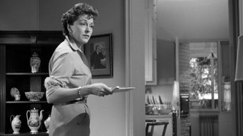 Movie still from “The Bad Seed” (1956), directed by Mervyn LeRoy – An old photo of an older woman holding a tablet; Medium shot, Over the shoulder angle