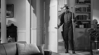 Movie still from “The Bad Seed” (1956), directed by Mervyn LeRoy – A black and white photo of a man holding a cane; Medium shot, Low angle