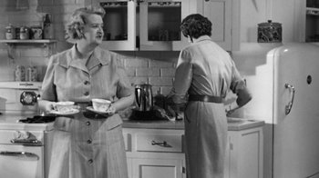 Movie still from “The Bad Seed” (1956), directed by Mervyn LeRoy – Two women are standing in a kitchen preparing a meal; Medium shot, Low angle