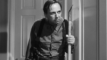 Movie still from “The Bad Seed” (1956), directed by Mervyn LeRoy – A black and white photo of a man holding an arrow; Medium shot, Low angle