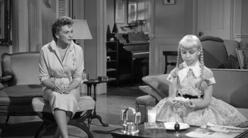 Movie still from “The Bad Seed” (1956), directed by Mervyn LeRoy – Two women sitting in a living room , one of whom is holding a baby; Wide shot, Over the shoulder angle