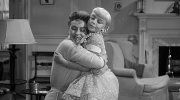 Movie still from “The Bad Seed” (1956), directed by Mervyn LeRoy – A black and white photo of a woman hugging a little girl; Medium shot, High angle