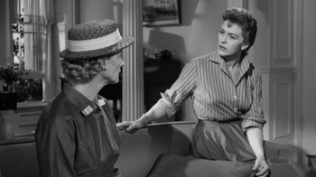 Movie still from “The Bad Seed” (1956), directed by Mervyn LeRoy – Two women are talking in a room with a mirror in the background; Medium shot, Over the shoulder angle