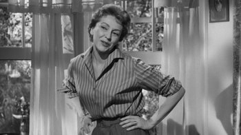 Movie still from “The Bad Seed” (1956), directed by Mervyn LeRoy – An older woman standing in front of a window with her hands on her hips; Medium shot, Low angle