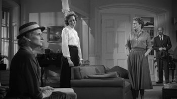 Movie still from “The Bad Seed” (1956), directed by Mervyn LeRoy – A group of people sitting around a living room together; Medium shot, Over the shoulder angle