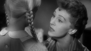 Movie still from “The Bad Seed” (1956), directed by Mervyn LeRoy – A black - and - white photo of a woman brushing her hair; Close Up shot, Over the shoulder angle