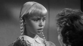 Movie still from “The Bad Seed” (1956), directed by Mervyn LeRoy – A young girl with long blonde plaited pigtails; Close Up shot, Over the shoulder angle