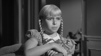 Movie still from “The Bad Seed” (1956), directed by Mervyn LeRoy – A young girl with pigtails is posing for a picture; Close Up shot, High angle