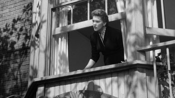 Movie still from “The Bad Seed” (1956), directed by Mervyn LeRoy – An old black and white photo of a woman looking out of a window; Medium shot, Low angle