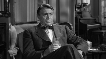 Movie still from “The Bad Seed” (1956), directed by Mervyn LeRoy – An older man sitting in a chair holding a glass of wine; Close Up shot, High angle