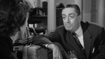 Movie still from “The Bad Seed” (1956), directed by Mervyn LeRoy – An older man sitting next to a woman in front of a suitcase; Close Up shot, Over the shoulder angle