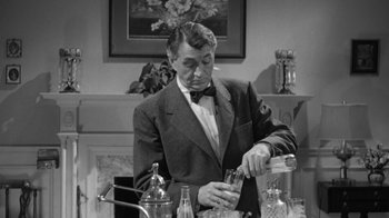 Movie still from “The Bad Seed” (1956), directed by Mervyn LeRoy – A black and white photo of a man pouring a drink into a glass; Medium shot, Low angle