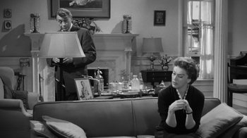 Movie still from “The Bad Seed” (1956), directed by Mervyn LeRoy – A man and a woman sitting on a couch in a living room; Medium shot, Over the shoulder angle