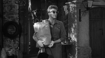 Movie still from “The Bad Seed” (1956), directed by Mervyn LeRoy – An old photo of a woman holding a paper bag; Medium shot, Low angle