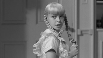 Movie still from “The Bad Seed” (1956), directed by Mervyn LeRoy – A young girl with pigtails holding a pair of scissors; Close Up shot, Over the shoulder angle
