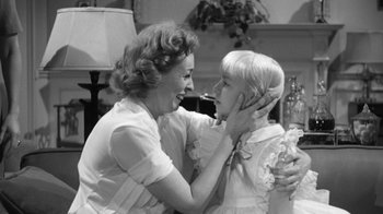 Movie still from “The Bad Seed” (1956), directed by Mervyn LeRoy – An older woman and a young girl smiling at each other; Medium shot, Over the shoulder angle