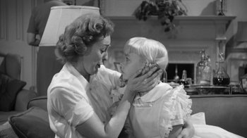Movie still from “The Bad Seed” (1956), directed by Mervyn LeRoy – An older woman and a young girl are touching each other's face; Medium shot, Over the shoulder angle