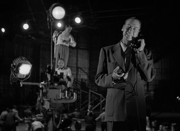 Movie still from “The Bad and the Beautiful” (1952), directed by Vincente Minnelli – A black and white photo of a man talking on a phone; Medium shot, Low angle