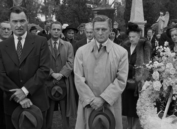 Movie still from “The Bad and the Beautiful” (1952), directed by Vincente Minnelli – Black and white photograph of a man in a trench coat; Medium shot, Low angle