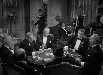 Movie still from “The Bad and the Beautiful” (1952), directed by Vincente Minnelli – A black and white photo of men in suits playing cards; Wide shot, High angle