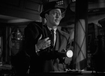 Movie still from “The Bad and the Beautiful” (1952), directed by Vincente Minnelli – A black and white photo of a man holding a light; Close Up shot, Low angle
