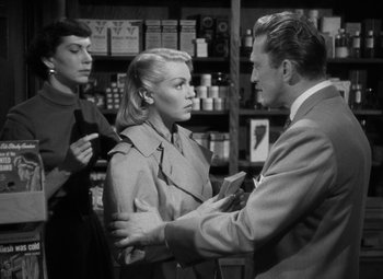 Movie still from “The Bad and the Beautiful” (1952), directed by Vincente Minnelli – A man and a woman in trench coats in a store; Medium shot, Over the shoulder angle
