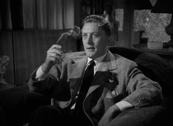 Movie still from “The Bad and the Beautiful” (1952), directed by Vincente Minnelli – A black and white photo of a man smoking a cigarette; Medium shot, High angle