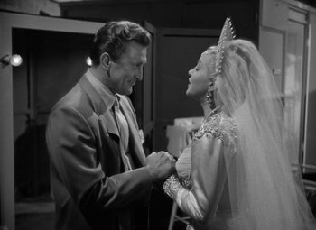 Movie still from “The Bad and the Beautiful” (1952), directed by Vincente Minnelli – A man and a woman holding hands in a black and white photo; Medium shot, Over the shoulder angle